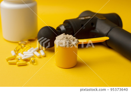Therapeutic percussive massage gun, fit meal, pills, sport energy bar, protein on yellow background - concept of modern sport activity and diet, health lifestyle routine, wellness, healthcare Therapeutic percussive massage gun, fit meal, pills, sport energy bar, protein on yellow background - concept of modern sport activity and diet, health lifestyle routine, wellness, healthcare 95373640