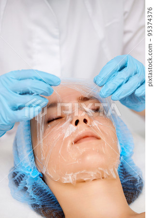 beautician applies the mask to the face of beautiful woman beautician applies the mask to the face of beautiful woman 95374376