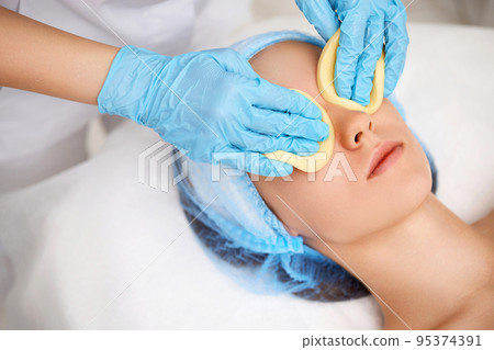 beautician cleanses skin of beautiful woman with a sponge. beautician cleanses skin of beautiful woman with a sponge. 95374391