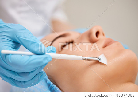 beautician applies the mask to face of beautiful woman 95374393