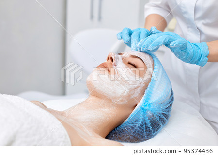 beautician applies the mask to the face of beautiful woman beautician applies the mask to the face of beautiful woman 95374436