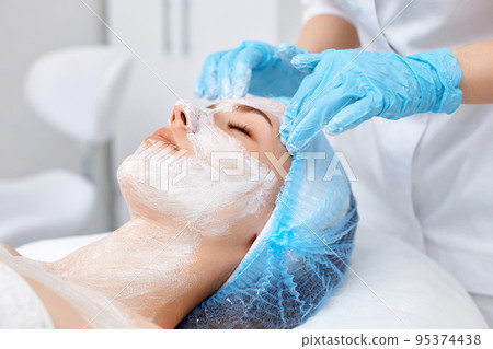 beautician applies the mask to the face of beautiful woman beautician applies the mask to the face of beautiful woman 95374438