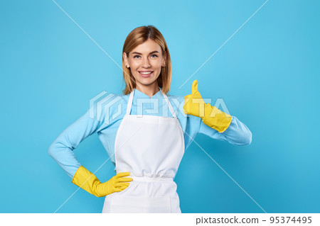 smiling blonde woman in yellow rubber gloves showing ok 95374495