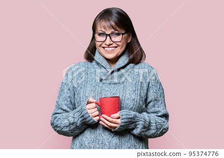 Winter portrait of happy woman in sweater with mug on pink color background 95374776