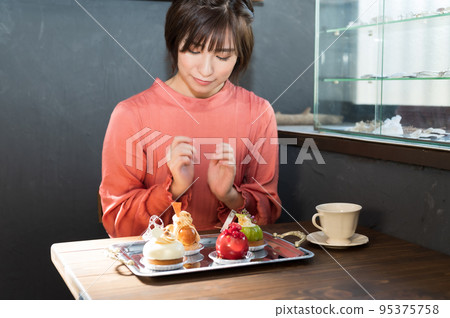 一個在咖啡館挑選蛋糕的女人 一個在咖啡館挑選蛋糕的女人 95375758
