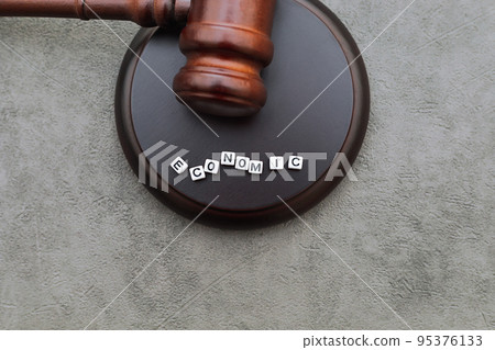 Economy Concept. Law theme. Judge gavel handcuffs and text word economic on grey table. Mallet of judge on concrete stone grey background. Economic crime in business financial crisis stock market 95376133