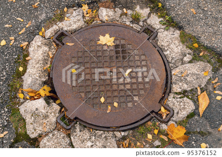 Old iron manhole cover on the street sewer cap Old iron manhole cover on the street sewer cap 95376152