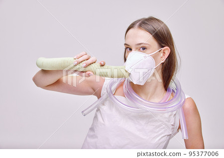 Close-up portrait of young beautiful girl taking deep breath in special mask isolated over grey background Close-up portrait of young beautiful girl taking deep breath in special mask isolated over grey background 95377006