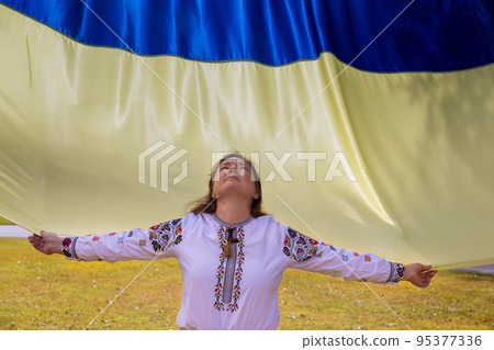 Young woman holds flag of Ukraine raising her head to heaven while praying for Ukraine 95377336
