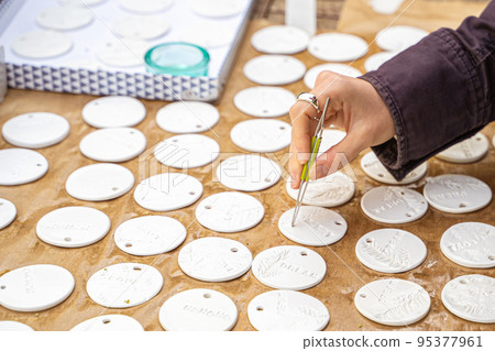 Young female artist creates round-shaped handmade ceramic decor on rustic market Young female artist creates round-shaped handmade ceramic decor on rustic market 95377961
