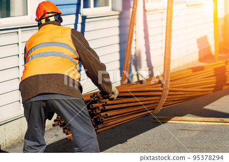 Slinger stacks thin metal pipes in stack on construction site. Close-up. Real workflow. Unloading of Slinger stacks thin metal pipes in stack on construction site. Close-up. Real workflow. Unloading of 95378294