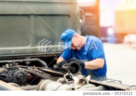 Mechanic in overalls repairs truck on summer day outside. Urgent repair of trucks. Authentic Mechanic in overalls repairs truck on summer day outside. Urgent repair of trucks. Authentic 95378321