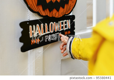 A kid with Carved pumpkin hanging on the fence of the house 95380441