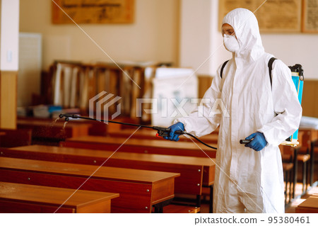 Disinfecting of office to prevent COVID-19, Man in protective hazmat suit with with spray chemicals. 95380461