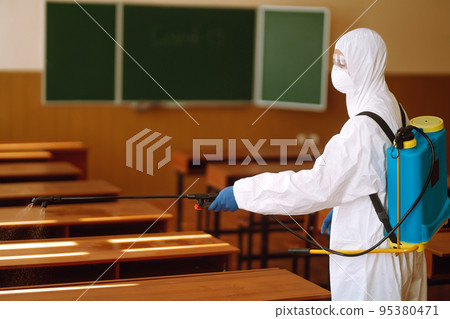 Disinfecting of office to prevent COVID-19, Man in protective hazmat suit with with spray chemicals. 95380471