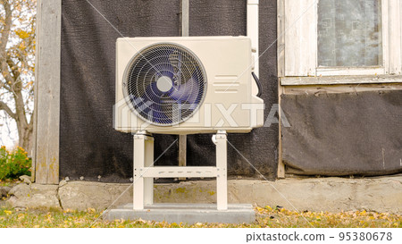 An air-to-air heat pump is installed on the exterior facade of the old house An air-to-air heat pump is installed on the exterior facade of the old house 95380678