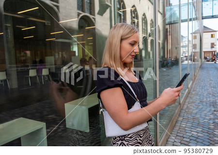 Happy blonde millennial girl in trendy clothes laughing on urban setting during sunny day, positive Happy blonde millennial girl in trendy clothes laughing on urban setting during sunny day, positive 95380729
