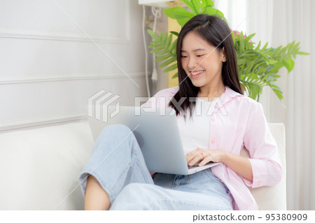 Young asian business woman work from home with laptop computer online to internet on sofa. 95380909