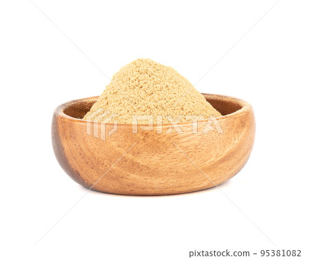 Wooden bowl with ground ginger root powder on a white background. 95381082