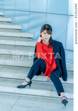 A young woman wearing red clothes sitting on the stairs Vertical position 95381094