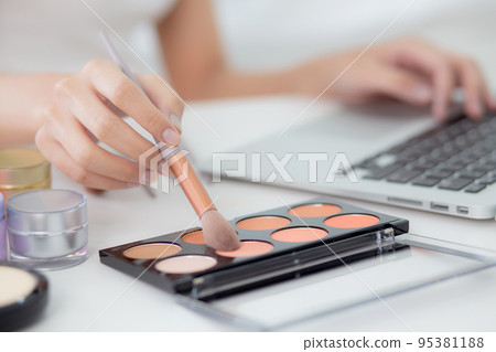 Hands of woman with learning makeup with brush on cheek on laptop computer with tutorial course. Hands of woman with learning makeup with brush on cheek on laptop computer with tutorial course. 95381188