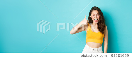Summer holidays and emotions concept. Cheerful young woman saying yes, praising good choice, nice work, showing thumbs up and looking excited, standing over blue background Summer holidays and emotions concept. Cheerful young woman saying yes, praising good choice, nice work, showing thumbs up and looking excited, standing over blue background 95381669