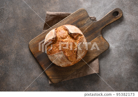 Loaf of freshly baked bread on brown background. 95382173