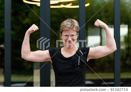 Portrait of a short haired white 35 yo woman showing her strong arms Portrait of a short haired white 35 yo woman showing her strong arms 95382718