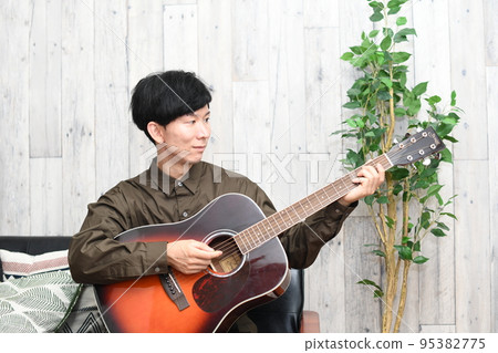 man playing guitar indoors 95382775