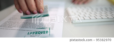 The hand puts the stamp approved on the document The hand puts the stamp approved on the document 95382970