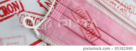 Red omicron stamp on a pink mask, close-up 95382990
