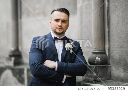Happy handsome smiling groom posing with boutonniere 95383929