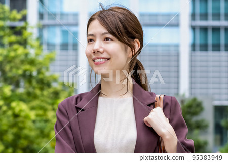 A smiling business woman walking in the office district 95383949