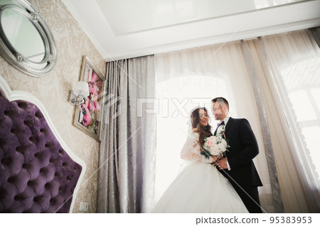 Beautiful young wedding couple posing with bouquet of flowers in hands 95383953