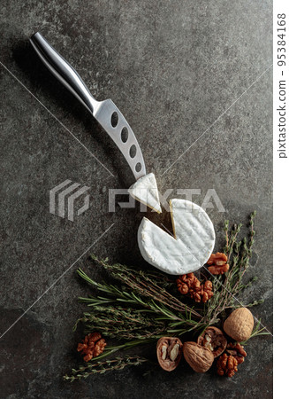 Brie cheese with walnuts, thyme, and rosemary on an old stone background. Brie cheese with walnuts, thyme, and rosemary on an old stone background. 95384168