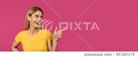 Smiling adult european woman with open mouth pointing finger at empty space 95384174