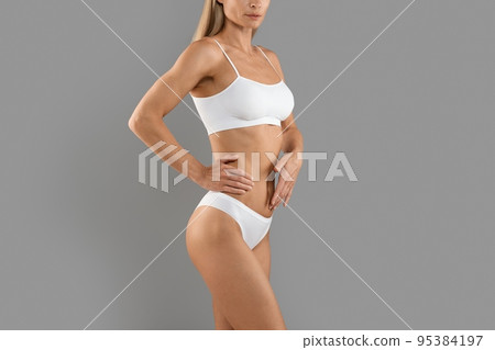 Body Care. Young Slim Woman In White Underwear Standing Over Grey Background Body Care. Young Slim Woman In White Underwear Standing Over Grey Background 95384197