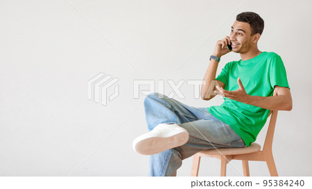 Ideas for business, modern work and communication. Young arab man talking on cellphone, sitting on chair over light wall 95384240