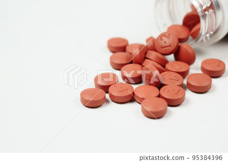 red color pain killer spilling form a container on white background  95384396