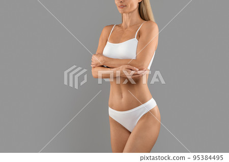 Cropped Shot Of Young Slim Woman In Underwear Standing On Grey Background Cropped Shot Of Young Slim Woman In Underwear Standing On Grey Background 95384495