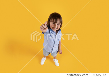 Above portrait of happy little boy pointing to camera with finger and smiling, choosing you, free space, full length 95385184