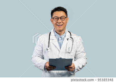 Cheerful middle aged korean man doctor in white coat and glasses with tablet, isolated on blue background Cheerful middle aged korean man doctor in white coat and glasses with tablet, isolated on blue background 95385348