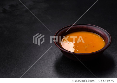 Delicious hot pumpkin and carrot soup puree with spices and herbs 95385679