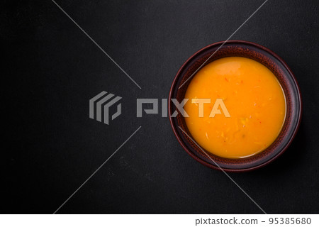 Delicious hot pumpkin and carrot soup puree with spices and herbs Delicious hot pumpkin and carrot soup puree with spices and herbs 95385680