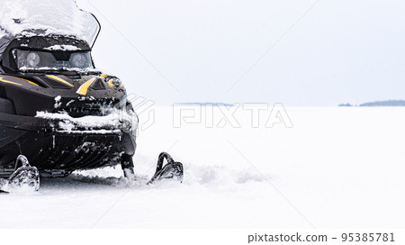 Panoramic background with snowmobile on ice of frozen lake on winter day Panoramic background with snowmobile on ice of frozen lake on winter day 95385781