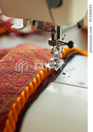 sewing machine. the process of sewing a decorative cord of red fabric. sewing machine. the process of sewing a decorative cord of red fabric. 95386683