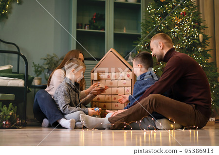 Family opens branches in Advent calendar with number 30 for new year. Countdown to most long-awaited magical winter holidays.  The tradition of receiving and giving gifts 95386913