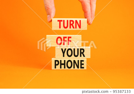 Turn off your phone symbol. Concept words Turn off your phone on wooden blocks. Beautiful orange background. Businessman hand. Business psychological turn off your phone concept. Copy space. Turn off your phone symbol. Concept words Turn off your phone on wooden blocks. Beautiful orange background. Businessman hand. Business psychological turn off your phone concept. Copy space. 95387133