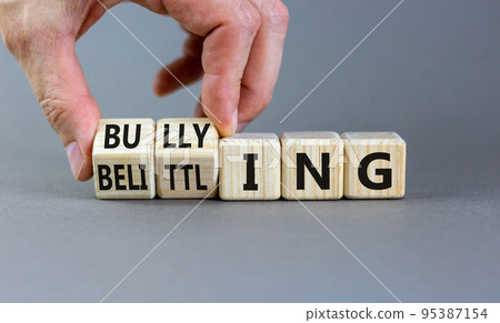 Bullying and belittling symbol. Concept words Bullying and Belittling on wooden cubes. Businessman hand. Beautiful grey table grey background. Business bullying and belittling concept. Copy space. Bullying and belittling symbol. Concept words Bullying and Belittling on wooden cubes. Businessman hand. Beautiful grey table grey background. Business bullying and belittling concept. Copy space. 95387154