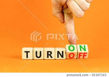 Turn on or off symbol. Concept words Turn off and Turn on on wooden cubes. Beautiful orange table orange background. Businessman hand. Business Turn on or off concept. Copy space. 95387165